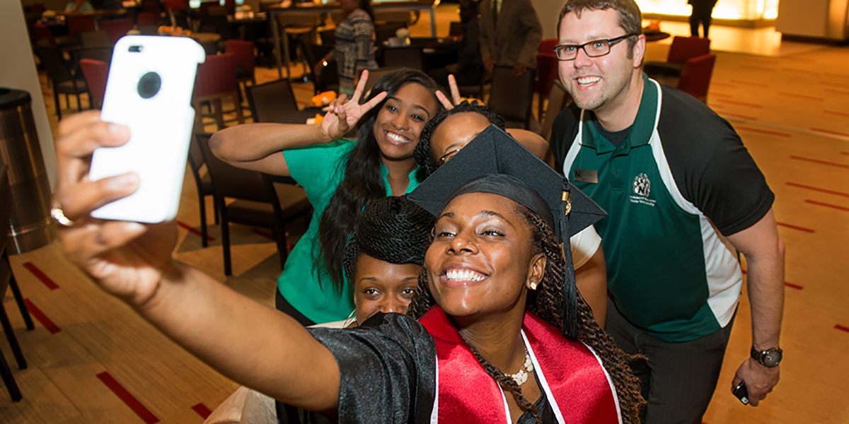 A Kauffman Scholars graduate takes a selfie with friends and family at graduation.