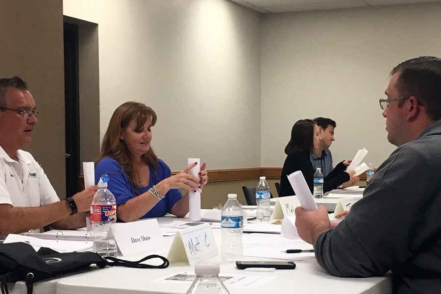 A group of three converse around a table during a NetWork Kansas Growing Rural Businesses event.