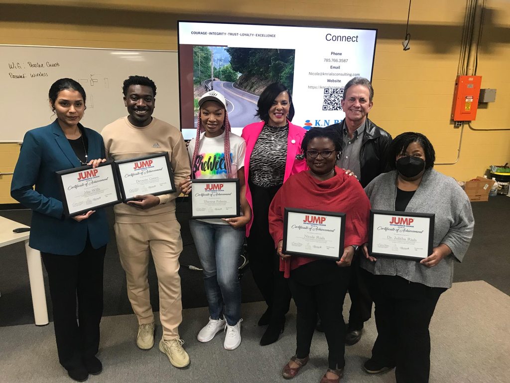 Kira Hopkins stands with a group of entrepreneurs who hold certificates of achievement.