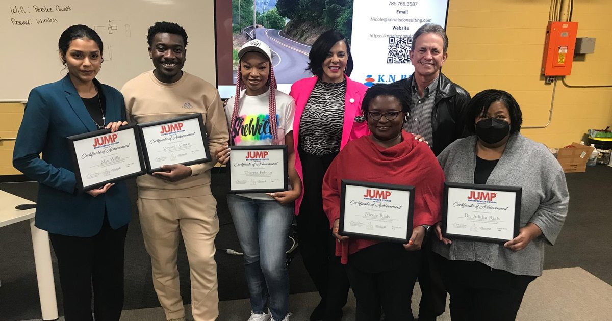 Kira Hopkins stands with a group of entrepreneurs who hold certificates of achievement.