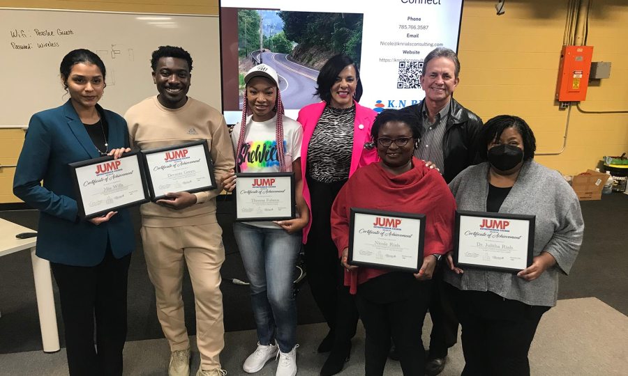 Kira Hopkins stands with a group of entrepreneurs who hold certificates of achievement.
