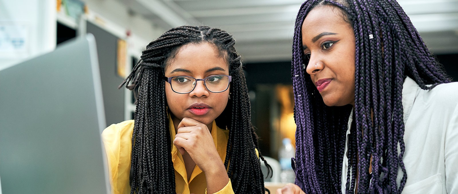 Two young people sit in front of a shared laptop.