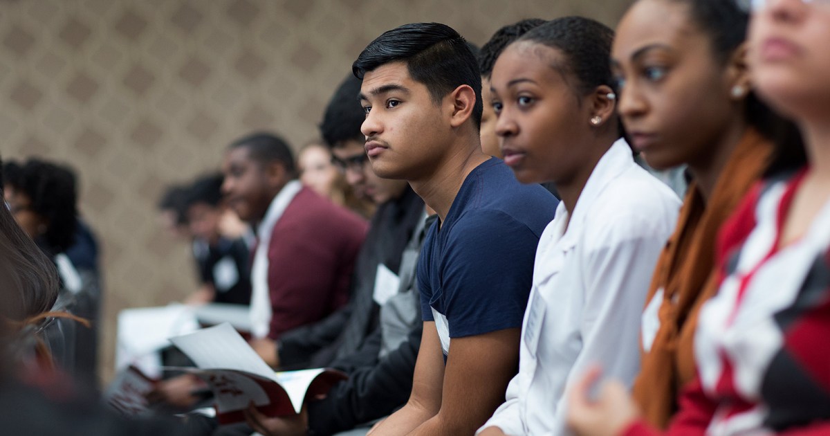 A group of young people sit side-by-side.