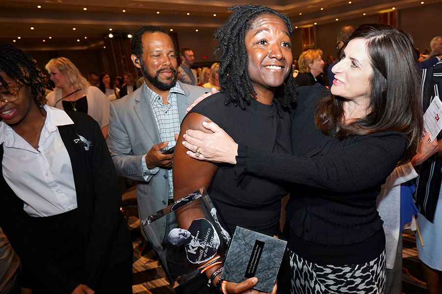 Fahteema Parrish, president and founder of Parrish & Sons Construction, holds the Mr. K Award she received at the KC Chamber Small Business Celebration, and is embraced by Lisa Ginter, CEO of Community America Credit Union.