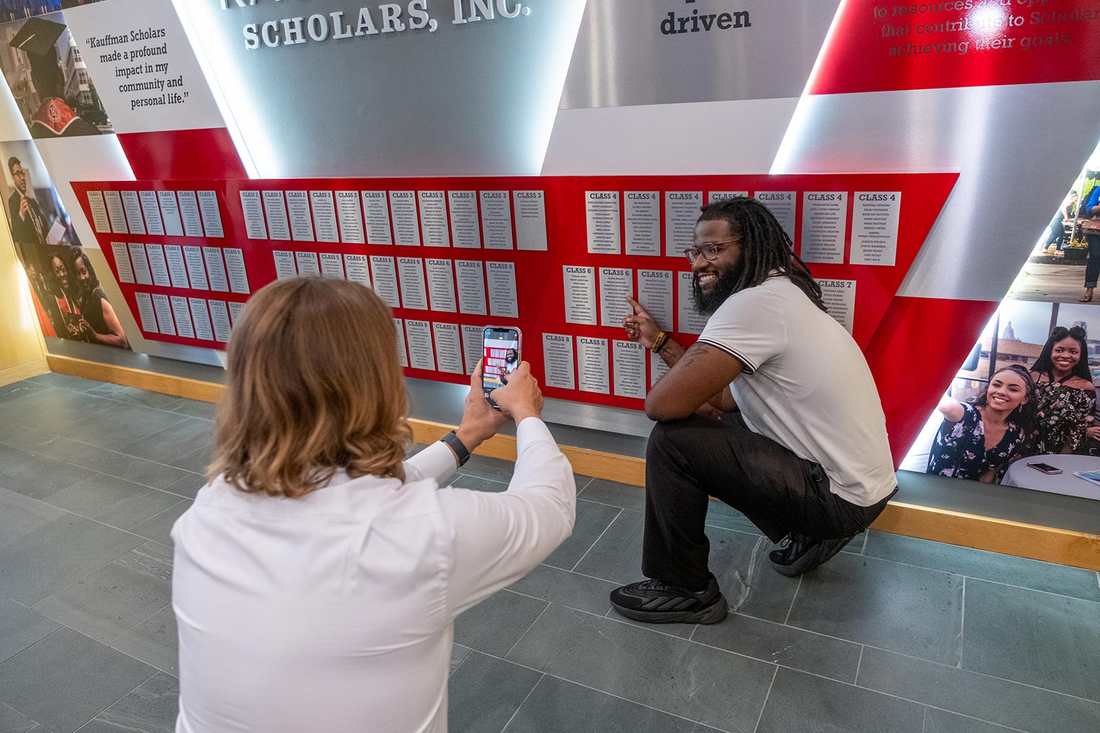 Kauffman Scholars alum poses for a photo in front of the KSI Legacy Wall in the Kauffman Foundation Conference Center.