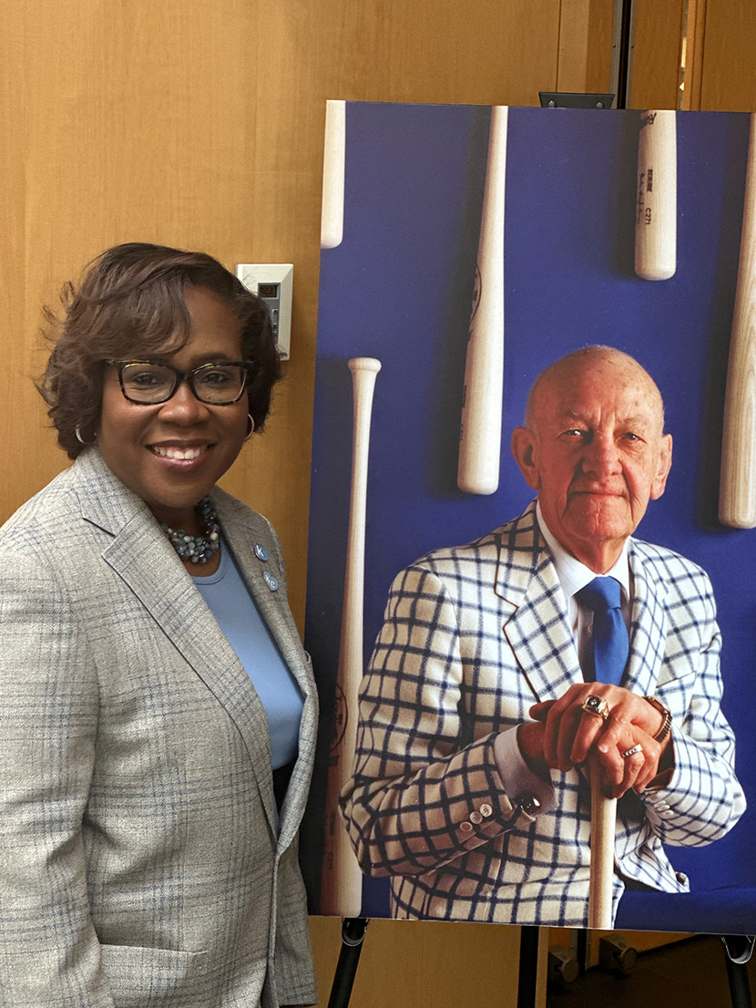 Dr. DeAngela Burns-Wallace stands next to a photo of Ewing Marion Kauffman.