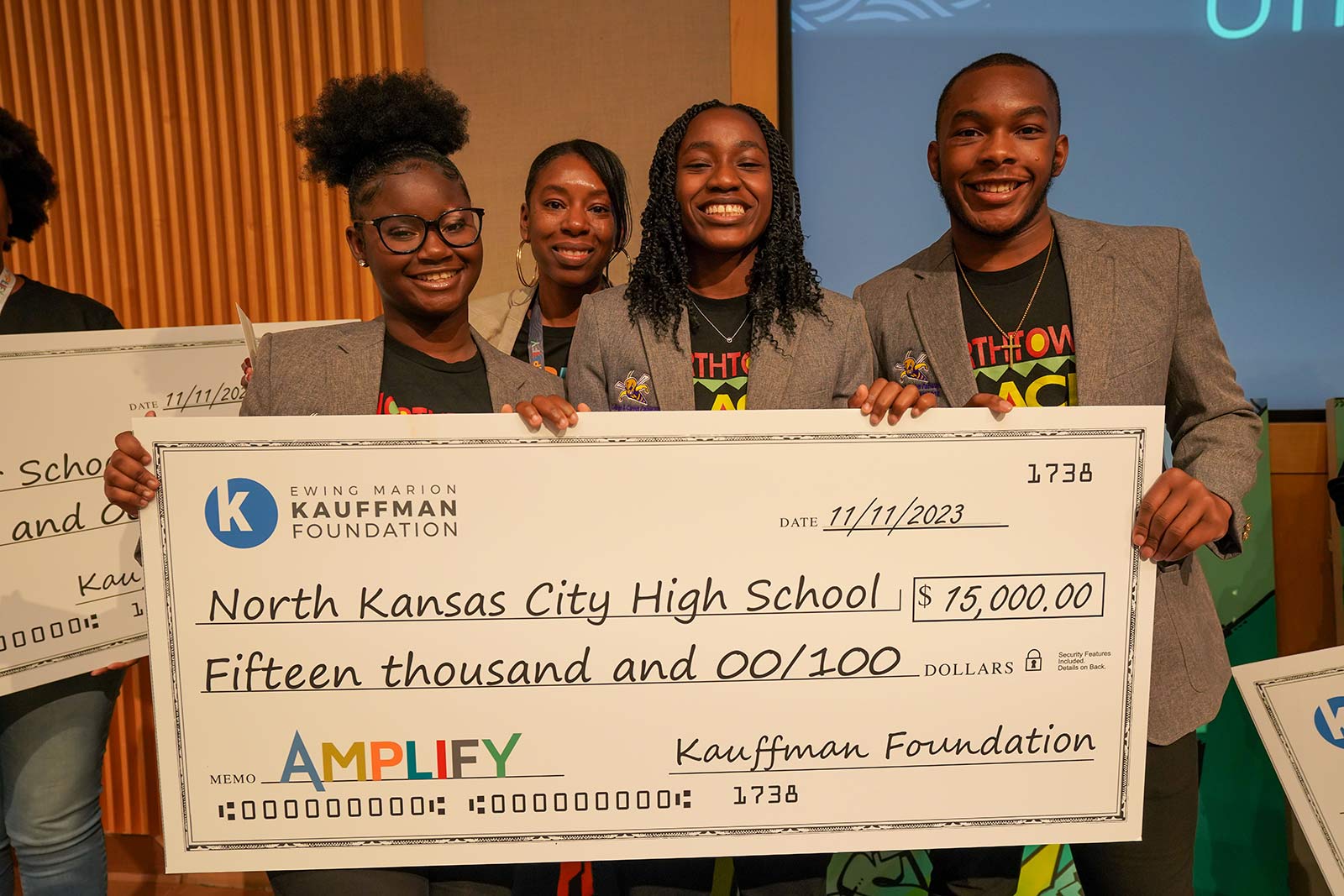 Amplify KC attendees hold a life-sized check made out to North Kansas City High School for $15,000 from the Kauffman Foundation