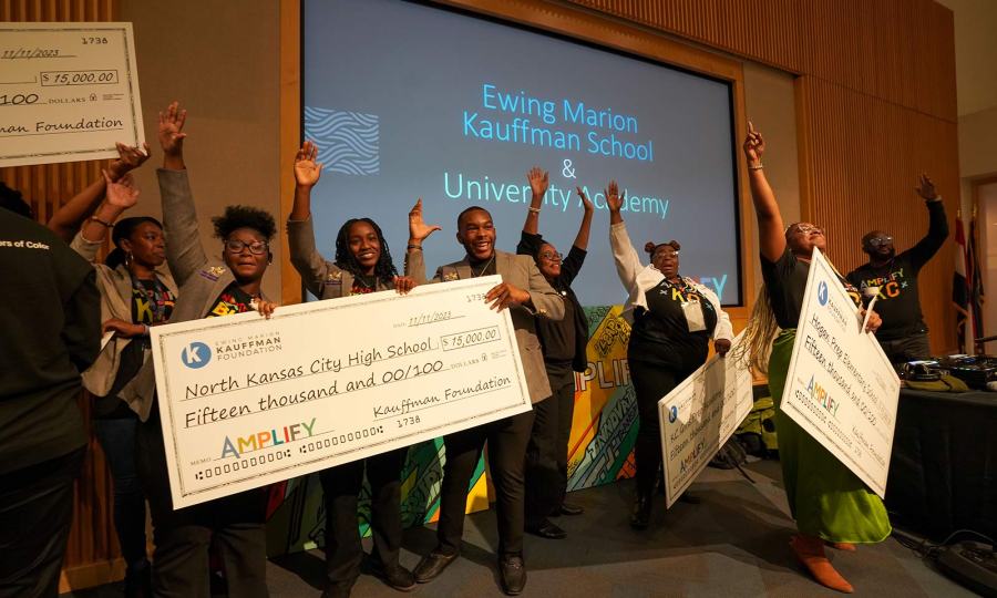 Educators and students from Brookside Charter School, Hogan Preparatory Academy, Kansas City Girls Preparatory Academy, and North Kansas City High School celebrate with life-sized checks at the 2023 Amplify Conference.