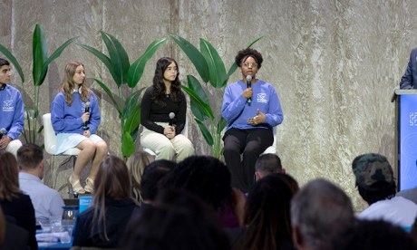 Students sit on a panel onstage with a facilitator