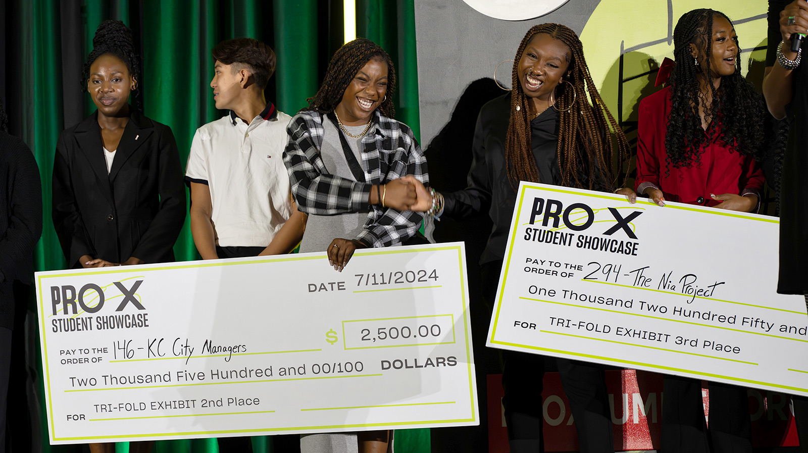 ProX interns hold life-sized checks at the ProX showcase event.