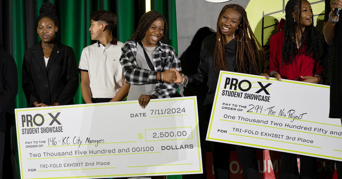 ProX interns hold life-sized checks at the ProX showcase event.