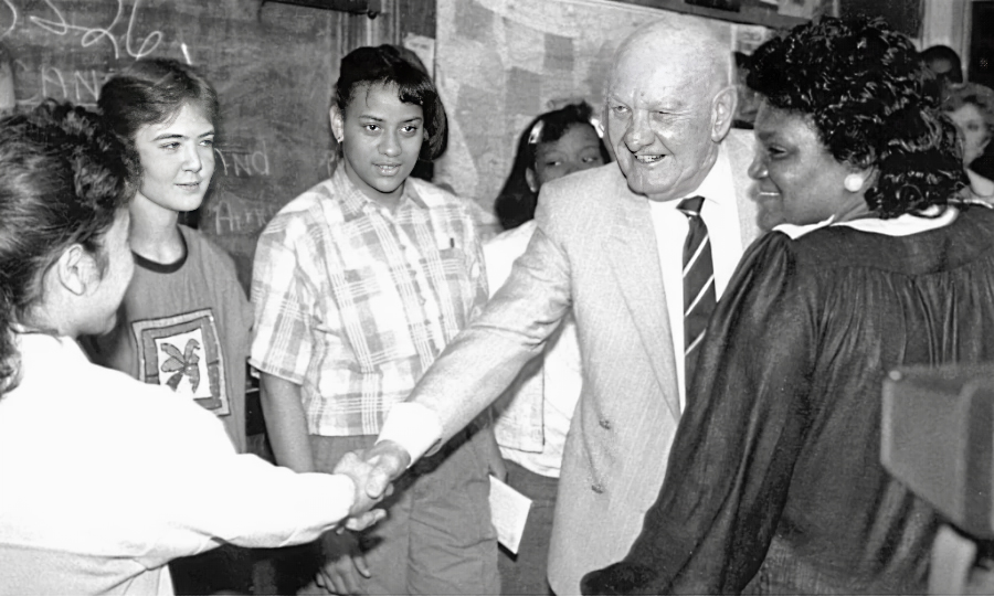 Mr. Kauffman shakes hands with a student in a classroom.